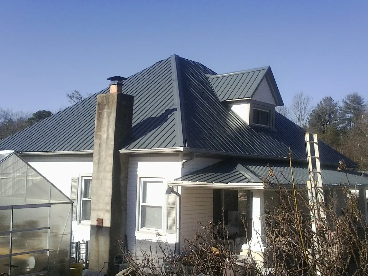 Dark blue standing seam metal roof on a white farmhouse with dormer — Slate & Tile Roof Repair by Roofing Brothers in Godwin