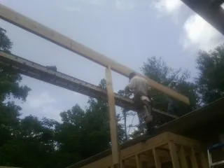 Carpenter setting a ridge beam over a new addition frame — Ice Dam Removal by Roofing Brothers in Godwin