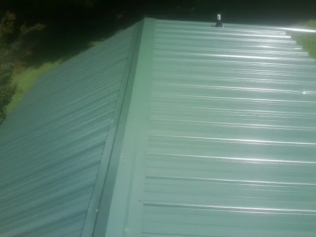New green metal panels meeting at the ridge of a roof — Flat Roof Repair work by our crew in Godwin
