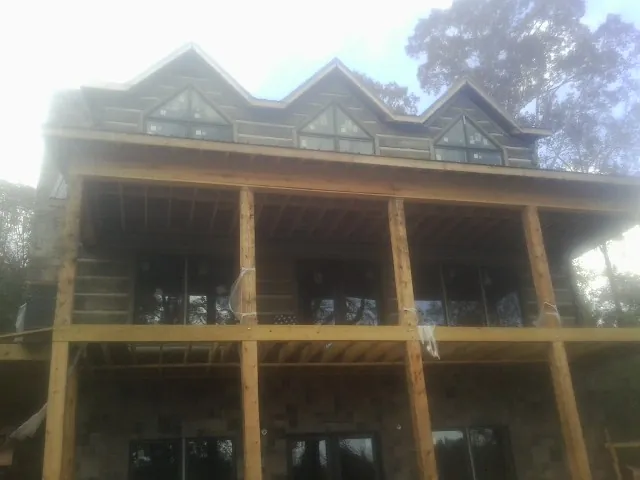 Dormers and porch framing on a large log home under construction — Roof Coating work by our crew in Godwin
