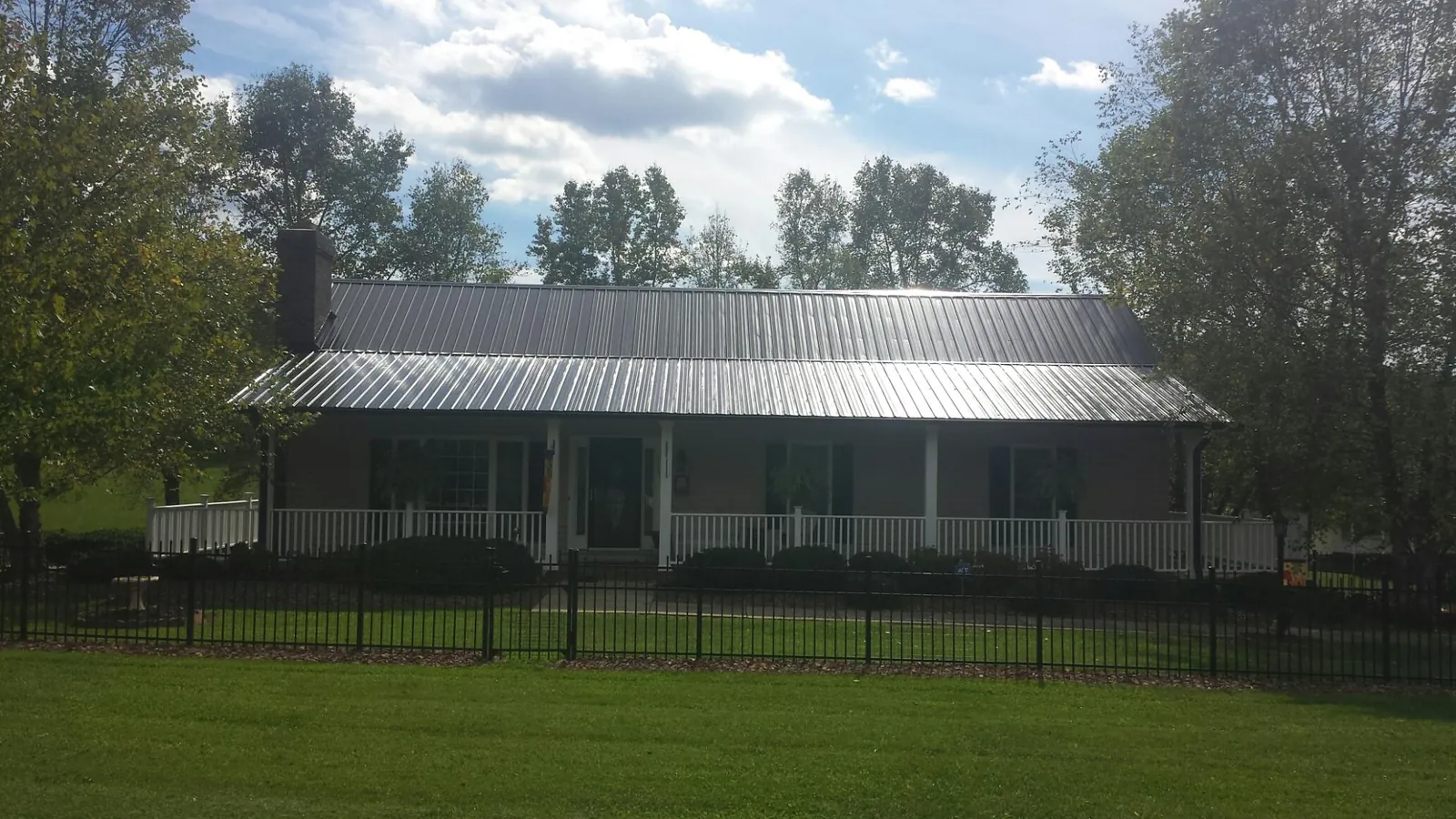 Gray metal roof on a brick ranch with a full width front porch — Gutter Guard Installation work by our crew in Godwin